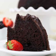 a slice of chocolate cake on a white plate with strawberries next to the cake