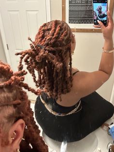 a woman with dreadlocks taking a selfie in front of a mirror while sitting at a table