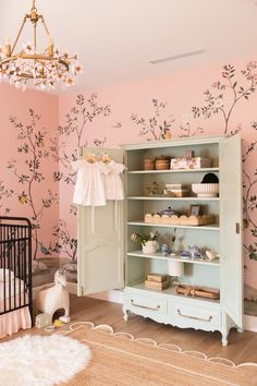 a baby's room with pink walls and floral wallpaper