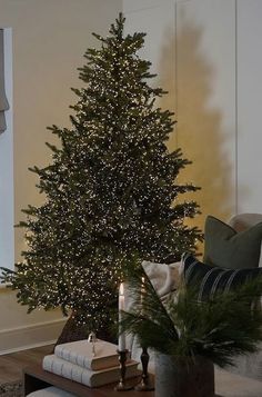 a living room with a lit christmas tree in the corner and pillows on the floor