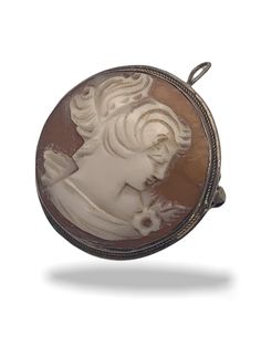 "Very vintage European carved shell cameo pin, with folding bale loop to hang from a chain as a necklace. It is a round, a much harder to find departure from the usual oval, and is set in sturdy 800 silver bezel Is very well carved with nice relief and great attention to detail: She has her elegant hairstyle and dress adorned with flower and leaf,  is a bit of a departure from the usual female head. The cameo is the image of a nostalgic moment for the beautiful lady, the head reclined towards th Vintage Pendant Locket Brooch, Silver Cameo Jewelry With Round Pendant, Vintage Locket Pendant Brooch, Antique Cameo Medallion Brooches, Silver Cameo Oval Pendant Jewelry, Antique Cameo Medallion Brooch, Vintage Hallmarked Pendant Brooches, Formal Cameo Pendant Brooch, Oval Silver Cameo Brooch