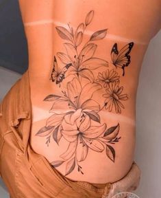 a woman's lower back with flowers and butterflies on her stomach, as if it were tattooing