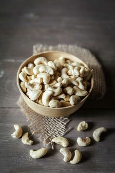 a wooden bowl filled with cashews on top of a table