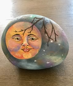 a painted rock with the face of a woman's face on it, sitting on a table