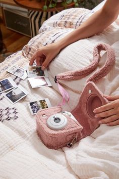 a person laying in bed with some pictures and a camera on top of the bed