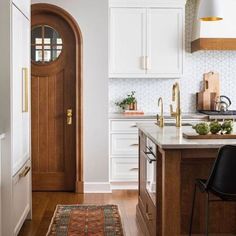 a kitchen with white cabinets and wooden flooring next to a counter top on an area rug