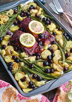 a pan filled with meat and vegetables on top of a table next to utensils