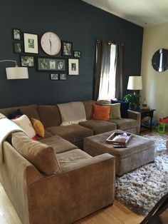 a living room filled with lots of furniture next to a wall mounted clock and pictures on the wall