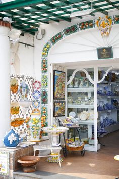 a store front with lots of plates and vases on it's display shelves