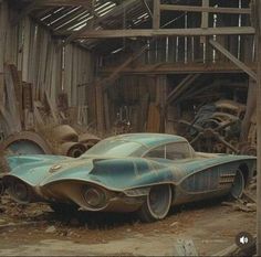 an old car sitting in the middle of a barn