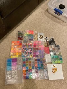 there are many different colors of beads on the floor next to some boxes and containers