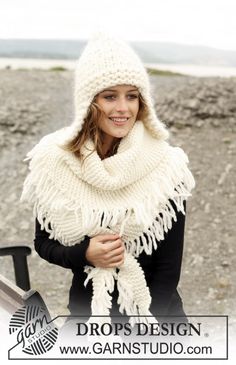 a woman wearing a white knitted hat and scarf standing in front of a car