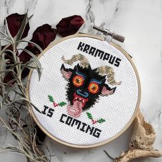 a cross - stitch pattern with the words kramus is coming on it next to dried flowers