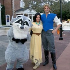 a man and woman standing next to a racoon mascot