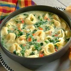 a bowl filled with pasta and spinach on top of a table