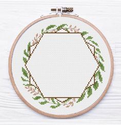 a cross stitch pattern with an oval frame in the middle and green leaves on it