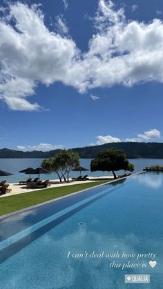 an empty swimming pool in front of a large body of water with trees on the other side