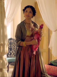 a woman standing in front of a bed holding a stuffed animal