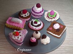 there are many cupcakes on the plate with crocheted decorations around them