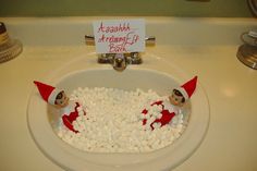 an elf is sitting in a bowl of marshmallows on the bathroom sink