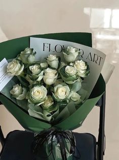 a bouquet of white roses sitting on top of a black chair next to a sign