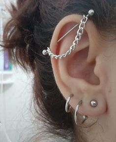 a close up of a person's ear with some piercings on it