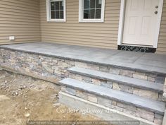 a stone wall and steps in front of a house that is being built into the ground