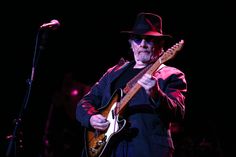 a man with a hat and guitar on stage