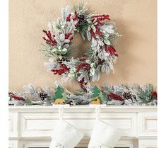 a christmas wreath and stockings hanging on a mantel