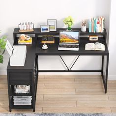 a computer desk with a laptop and other office supplies on it, in front of a white wall