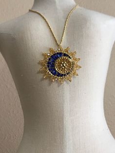 "Sun & Moon Beaded Celestial Statement Necklace.  This unique pendant is an inspirational and captivating statement piece.  It is a dramatic and eye-catching Made to Order piece which captures a delicate cool blue moon in front of a brilliant golden sun.  The pendant is stationary on a neckline of galvanized gold tiny seed beads and fastens with a gold plated lobster claw.  The pendant diameter is approximately 1 3/4\".  The shades of blue may vary.  Choose your desired length at checkout.  The pendant is dipped in floor wax to prevent the sun rays from flopping.  All materials used are Nickel/Lead Free.  Designed by Sara Landry, Dragonfly Lane and brought to life by Krina Kreations."