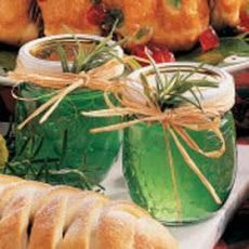 jars filled with green liquid sitting on top of a table next to bread and fruit