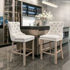 two white bar stools sitting in front of a counter