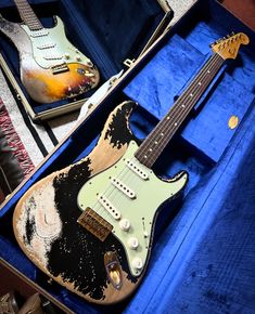 an electric guitar is in a case on the floor next to another one that has been painted