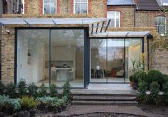 a house with glass walls and steps leading to the front door that leads into the back yard