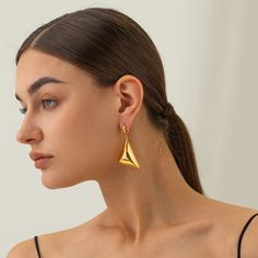 Meet your new statement piece: the Vanguard Gold Earrings. These sleek, geometric beauties are designed to turn heads and elevate your style game. Crafted with a high-shine 18 karat gold finish, these earrings feature a bold triangular design that dangles elegantly, creating a modern and sophisticated look. The unique pyramid shape of the earrings adds an edgy flair, making them perfect for both casual and formal outfits. Notice how they catch the light beautifully, highlighting the clean lines Pyramid Shape, Formal Outfits, Formal Outfit, Clean Lines, Gold Finish, Contemporary Design, Timeless Elegance, Gold Earrings, Silver Earrings