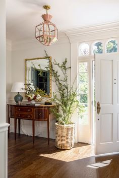 a room with a table, mirror and potted plant