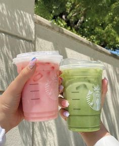 two people holding cups with drinks in them