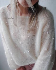 a woman wearing a white sweater with pearls on it