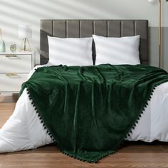 a bed covered in a green blanket and pillows