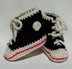 two black and white crocheted shoes with red trims sitting on top of each other