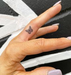 a woman's hand with a small butterfly tattoo on her left thumb and finger