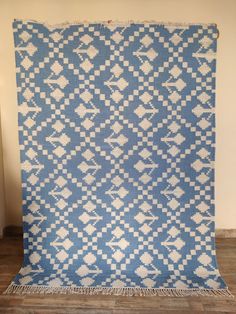 a large blue and white rug on top of a wooden floor next to a wall