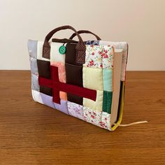 a handbag made out of patchwork fabric on a wooden table with a hook