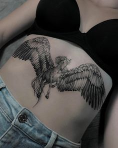 a woman with a tattoo on her stomach has a horse and wings tattooed on it