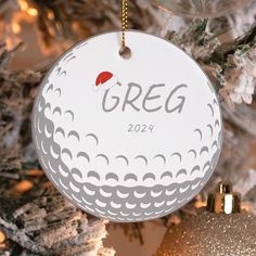 a golf ball ornament hanging from a christmas tree with ornaments around it and the words greg on it