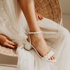 a woman sitting in a wicker chair wearing white shoes