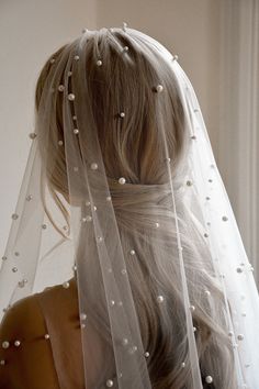 the back of a woman's head wearing a white veil with pearls on it