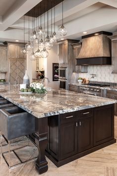 a large kitchen with marble counter tops and wooden cabinets, along with chandeliers hanging from the ceiling