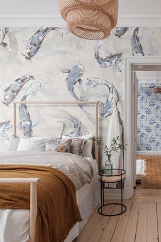 a bed sitting in a bedroom next to a wall with dolphins on it and a basket hanging from the ceiling